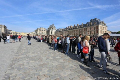 Long Queue of Visitors to Enter the Palace of Versailles, the Entrance is to the Left of the Photo